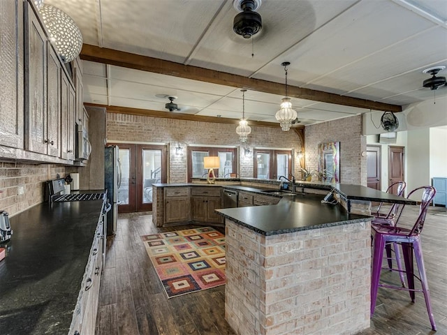 kitchen with dark hardwood / wood-style floors, a breakfast bar area, brick wall, and french doors