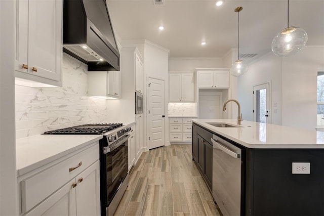 kitchen featuring wall chimney exhaust hood, appliances with stainless steel finishes, crown molding, white cabinetry, and a sink