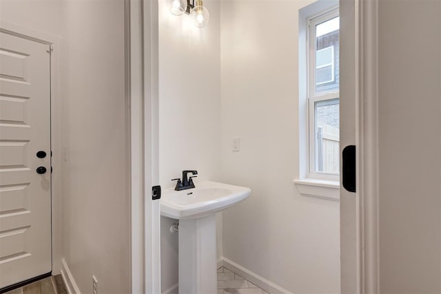 bathroom featuring a healthy amount of sunlight, a sink, and baseboards