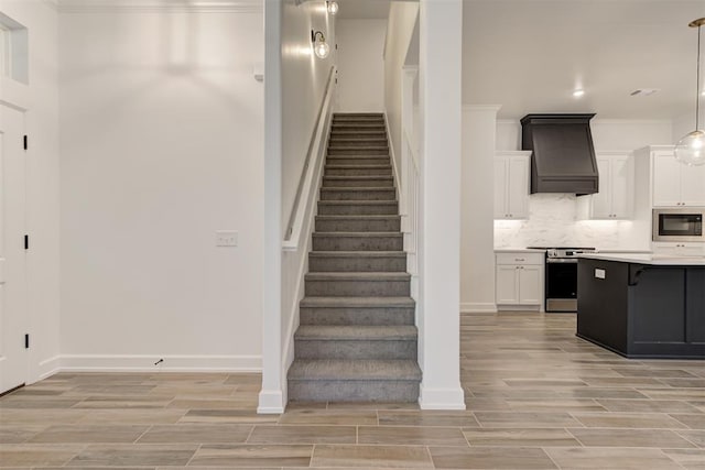 staircase with ornamental molding, wood tiled floor, and baseboards