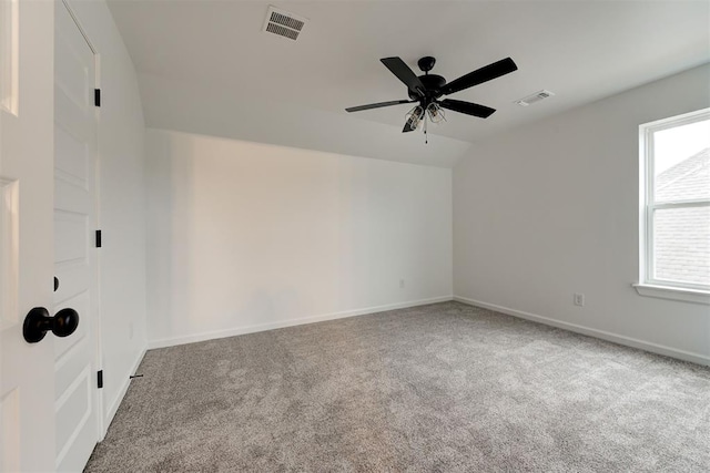 spare room featuring vaulted ceiling, carpet flooring, visible vents, and baseboards