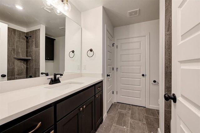 full bath featuring visible vents, tiled shower, and vanity