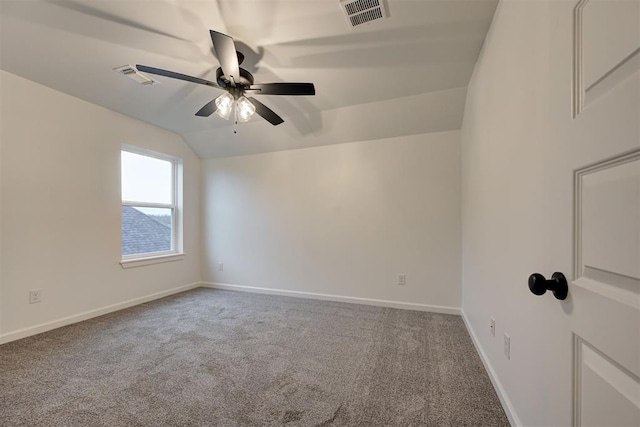 empty room with visible vents, baseboards, ceiling fan, vaulted ceiling, and carpet floors