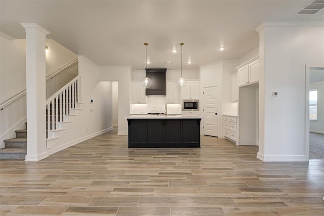 kitchen with tasteful backsplash, light countertops, visible vents, white cabinetry, and built in microwave