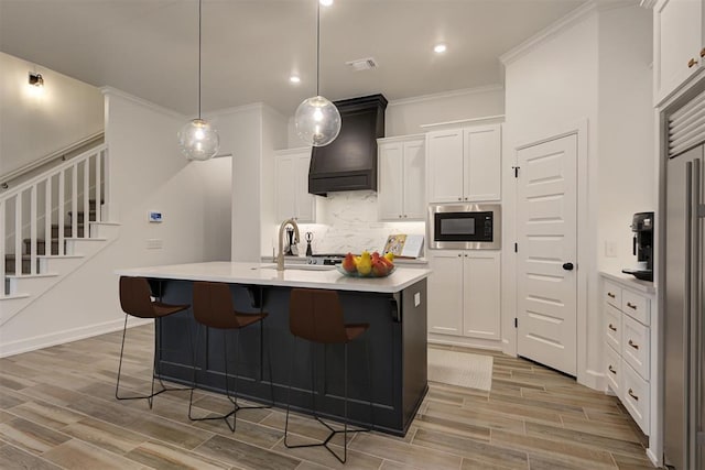 kitchen featuring built in appliances, white cabinetry, visible vents, light countertops, and wood tiled floor