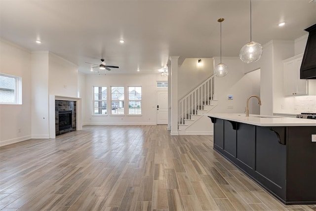 2348 Ridge Pine Rd, Edmond, OK 73034 - kitchen with light countertops, a breakfast bar, ceiling fan, a fireplace, and ornamental molding