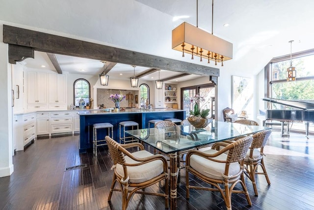 dining room featuring beam ceiling, plenty of natural light, and dark hardwood / wood-style floors