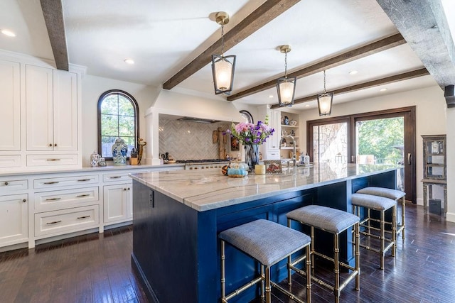 kitchen featuring beamed ceiling, a kitchen island with sink, and dark wood-type flooring