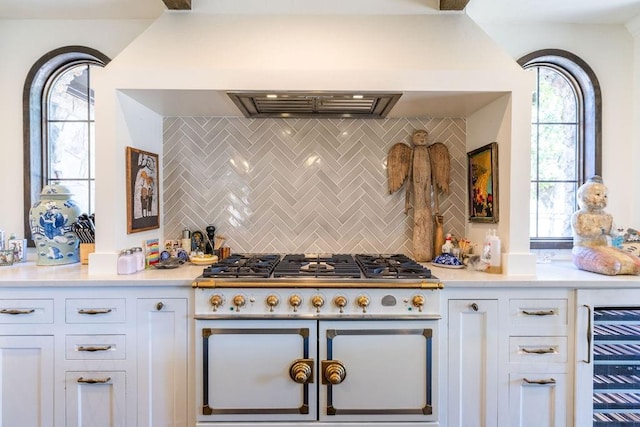 kitchen with white cabinets, a healthy amount of sunlight, and high end range