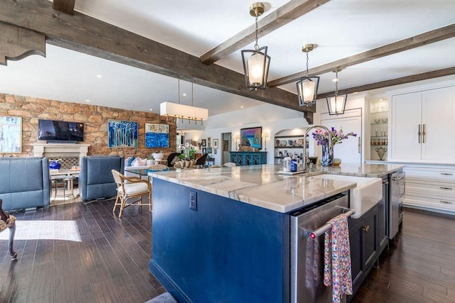 kitchen featuring a large island with sink, decorative light fixtures, light stone counters, and dark hardwood / wood-style floors