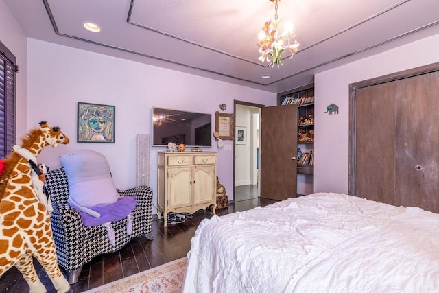 bedroom featuring dark hardwood / wood-style floors, an inviting chandelier, and a closet