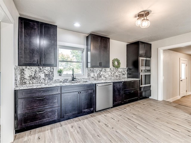 kitchen featuring backsplash, sink, light hardwood / wood-style flooring, dark brown cabinets, and stainless steel appliances