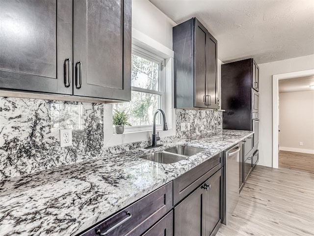 kitchen featuring decorative backsplash, light stone counters, dark brown cabinets, sink, and light hardwood / wood-style flooring