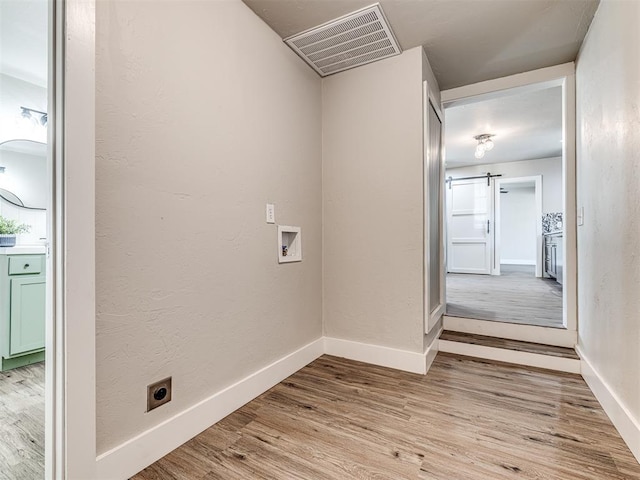 laundry area featuring a barn door, hookup for an electric dryer, washer hookup, and light wood-type flooring