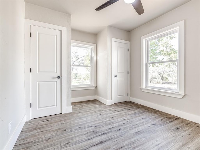 unfurnished bedroom featuring multiple windows, ceiling fan, and light hardwood / wood-style flooring