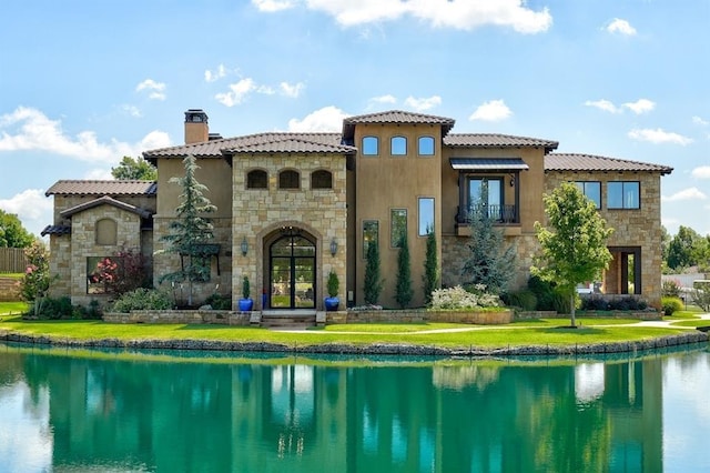 rear view of house with a water view, a yard, and french doors