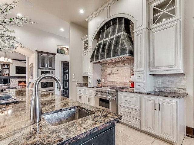 kitchen featuring tasteful backsplash, white cabinetry, stainless steel range, and dark stone counters