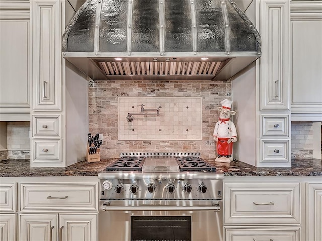 kitchen with dark stone countertops, decorative backsplash, high end stainless steel range, and custom range hood