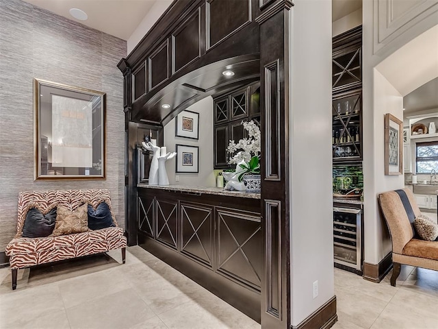 interior space with light tile patterned flooring, beverage cooler, and indoor bar