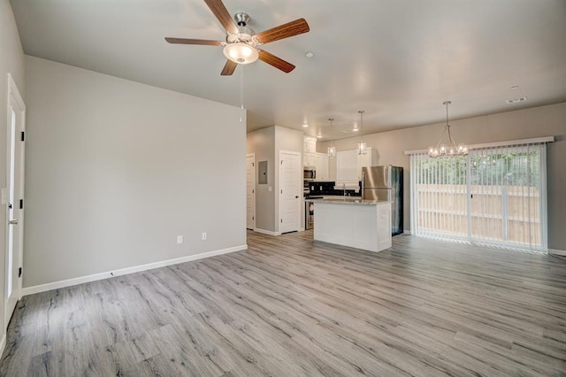 unfurnished living room featuring ceiling fan with notable chandelier, light hardwood / wood-style floors, and electric panel