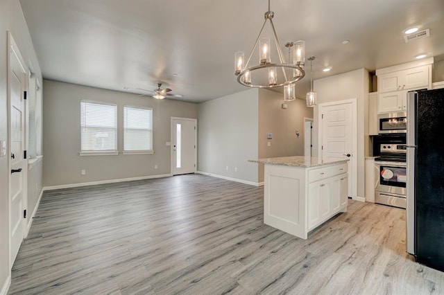 kitchen featuring appliances with stainless steel finishes, ceiling fan with notable chandelier, white cabinetry, and pendant lighting