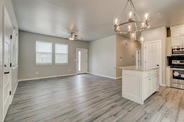 kitchen with white cabinetry, hanging light fixtures, stainless steel appliances, and ceiling fan with notable chandelier