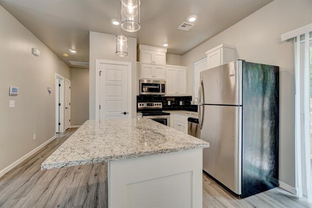 kitchen with a center island, hanging light fixtures, stainless steel appliances, backsplash, and white cabinets