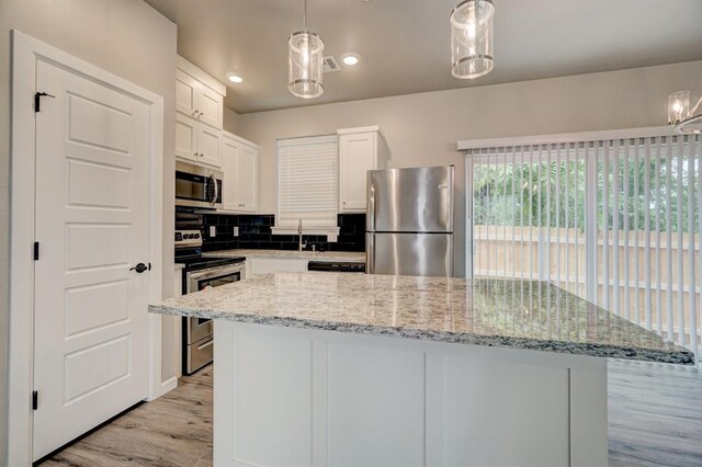 kitchen featuring white cabinets, decorative light fixtures, decorative backsplash, and appliances with stainless steel finishes