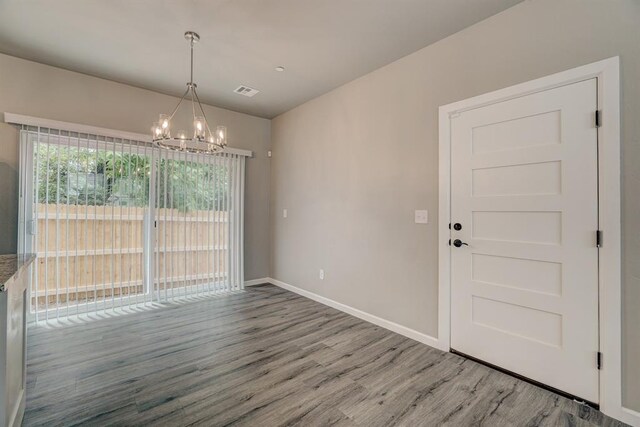 unfurnished dining area featuring hardwood / wood-style floors and a notable chandelier