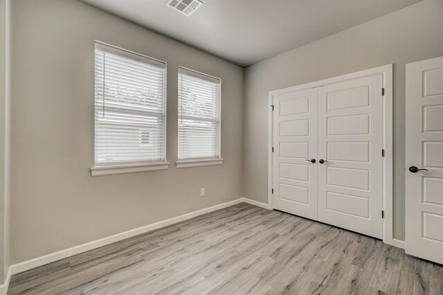 unfurnished bedroom featuring light hardwood / wood-style flooring and a closet