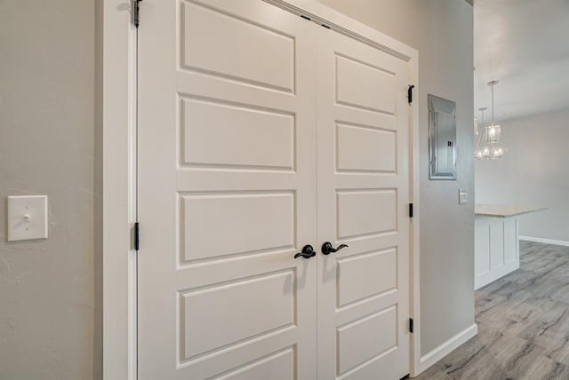 details with electric panel, hardwood / wood-style floors, and a chandelier