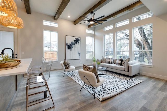 sunroom with ceiling fan, beam ceiling, and a wealth of natural light