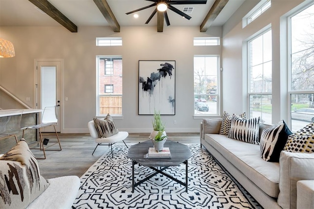 living room with hardwood / wood-style flooring, ceiling fan, and beamed ceiling