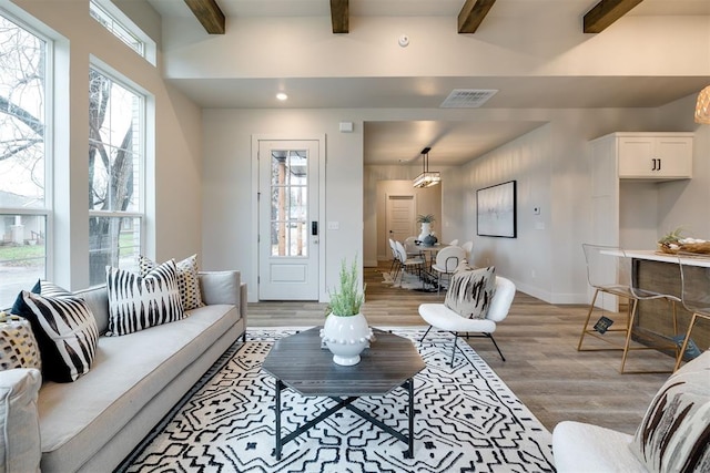 living room featuring beamed ceiling and light hardwood / wood-style floors