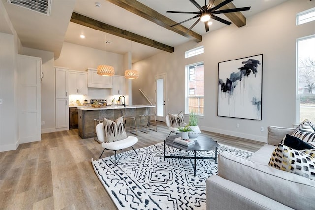 living room featuring ceiling fan, beamed ceiling, and light wood-type flooring