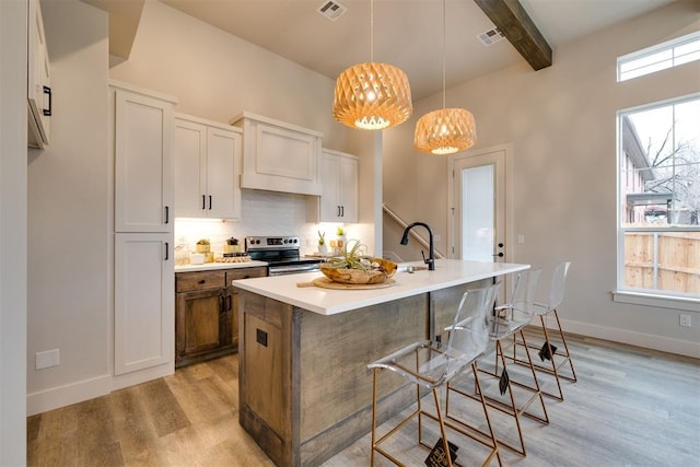 kitchen featuring a healthy amount of sunlight, electric stove, and a kitchen island with sink