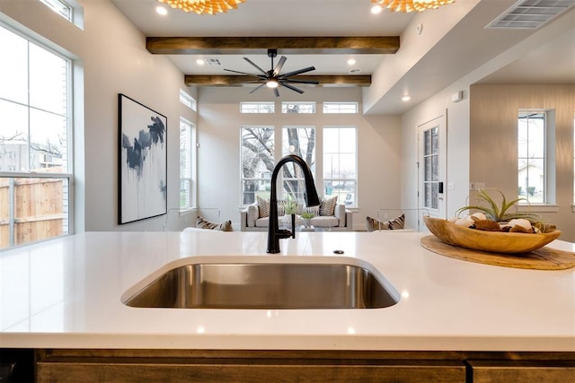 kitchen with sink, beamed ceiling, and plenty of natural light