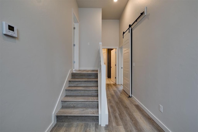 staircase featuring a barn door and hardwood / wood-style flooring