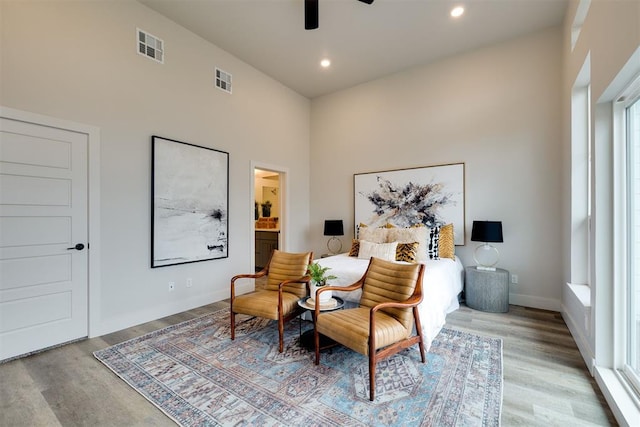 living area with a towering ceiling, light hardwood / wood-style floors, and ceiling fan