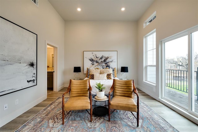 bedroom featuring hardwood / wood-style flooring, ensuite bathroom, access to exterior, and multiple windows