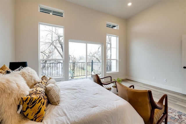 bedroom featuring access to exterior, light hardwood / wood-style flooring, and multiple windows