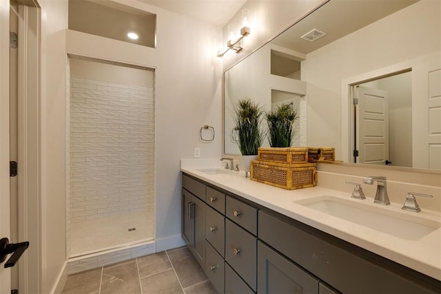 bathroom with a tile shower, tile patterned flooring, and vanity