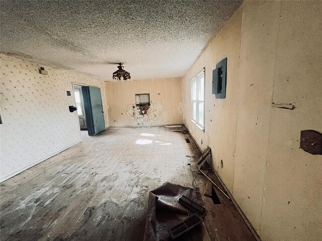 interior space featuring electric panel, wood-type flooring, and a textured ceiling