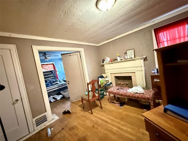 sitting room featuring a tiled fireplace, wood-type flooring, and a textured ceiling