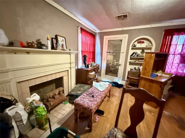 misc room with built in features, a textured ceiling, and a tile fireplace