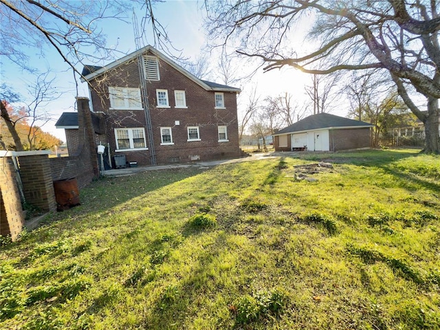 rear view of house featuring an outdoor structure, a garage, and a yard