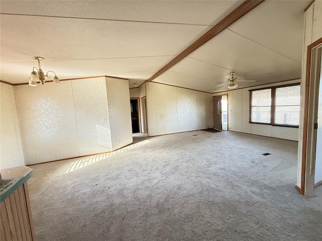 carpeted empty room with lofted ceiling with beams and ceiling fan with notable chandelier