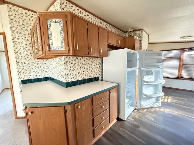 kitchen featuring baseboards, light countertops, dark wood-style flooring, and brown cabinets