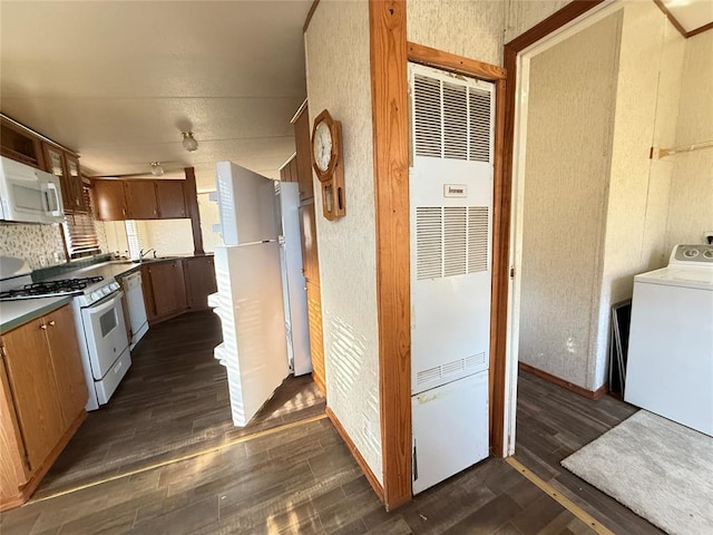 kitchen featuring washer / dryer, dark wood finished floors, white appliances, and a heating unit