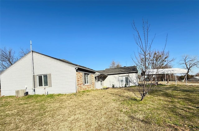 back of property featuring central air condition unit, a lawn, and a carport